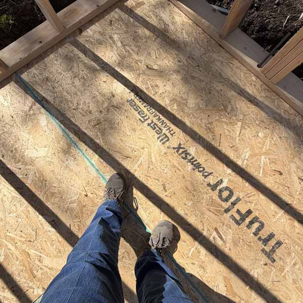 Standing in It Feet standing on a subfloor in an art studio under construction, with framing shadows across the floor